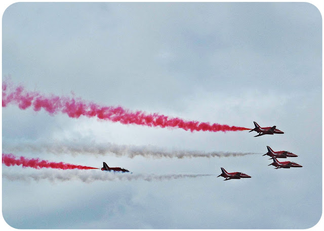 5 planes in sky with alternate red and white smoke