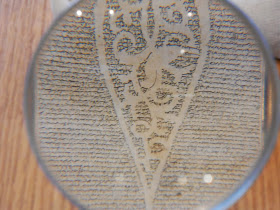 The scroll photographed through a magnifying glass, showing an abstract pattern created by the negative space in the text.