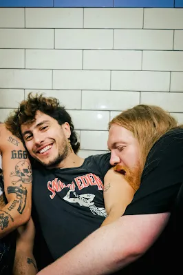 Two male colleagues sharing a relaxed and playful moment, symbolizing workplace diversity, social connection, and quality of work life for better team engagement in 2025.