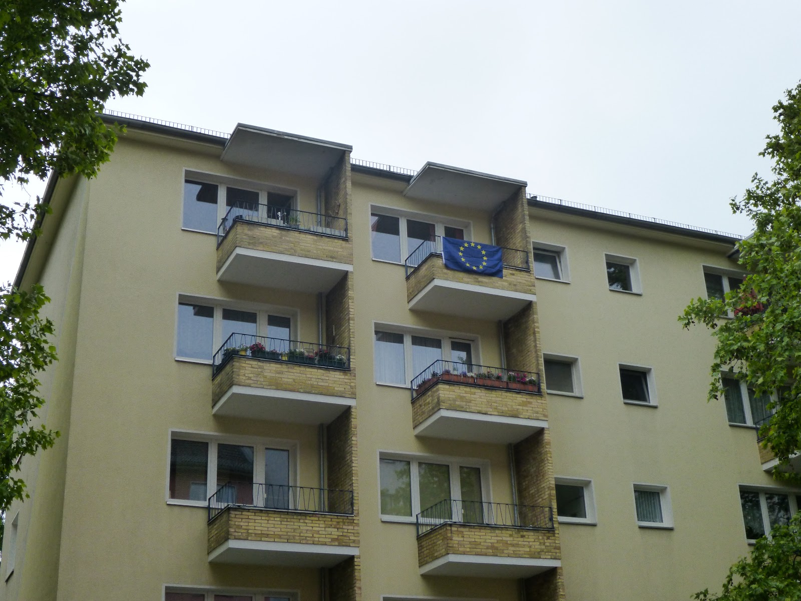 Multi-storey building with several balconies; an EU flag is attached to one of the balconies