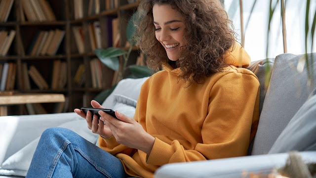 A woman sitting on a couch using her phone.