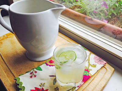 Glass of limeade with white pitcher