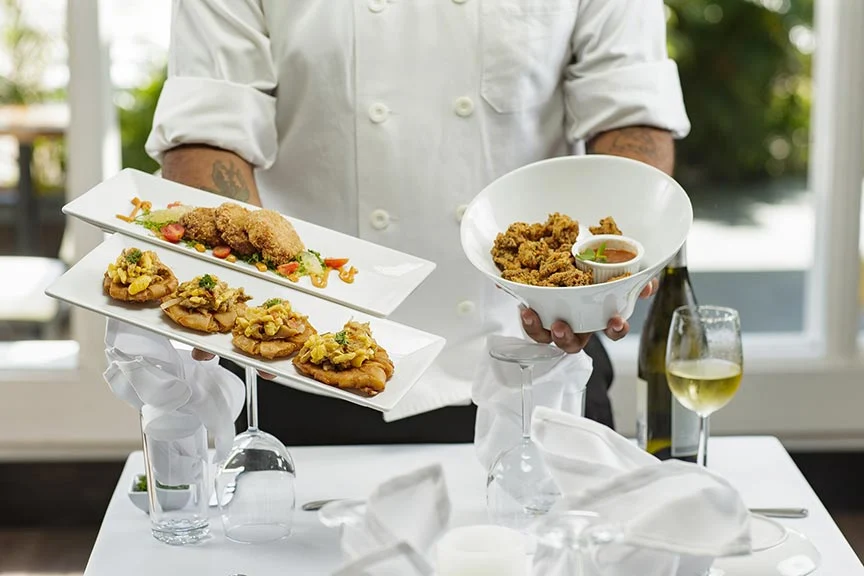 How much to hire a Personal Chef. Man holding white plates with food on.