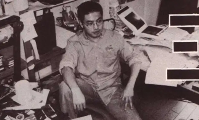 A black and white image of Berserk manga author Kentaro Miur slumped on his office surrounded by paperwork, drawing equipment and random clutter