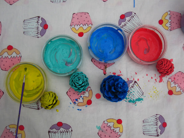 Paint in glass jars next to the pine cones painted in the same colour