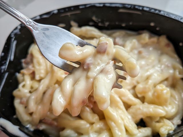 A forkful of Devour White Cheddar Mac & Cheese with Bacon.