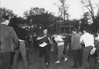 A photograph of a crowd of men outside, some running.