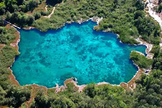 Vista aerea de una laguna super transparente rodeada de vegetación exhuberante