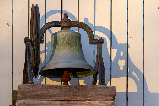 tarnished brass bell on wood stand