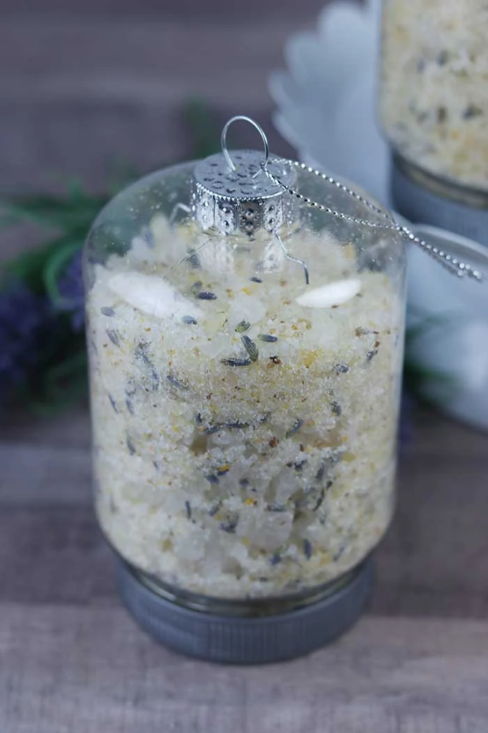 How to make an easy lemon lavender bath salts recipe with essential oils. These use aromatherapy to promote calming and stress relief and other benefits.  They are easy to make with Epsom salt, sea salt, essential oils, lavender, and dried citrus peels. This makes a great Christmas DIY gift with cute container ideas with tiny mason jar ornaments for containers. Give the gift of homemade relaxing detox herbal bath salts for Christmas. #bathsalts #diy #gift #lemon #lavender