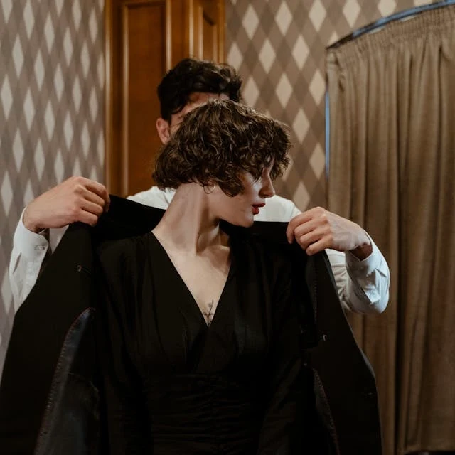 Men helping a woman in a black evening gown into a coat