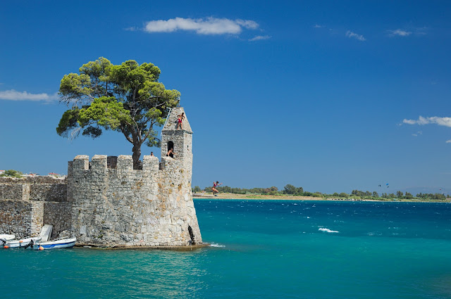 The entrance of the port with teenagers falling from the stone wall, in Nafpaktos, Greece.