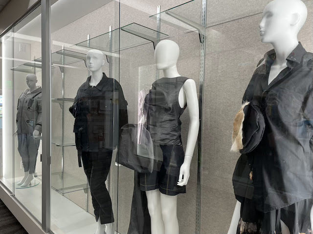 A display case with mannequins wearing different kinds of fashion in black and grey