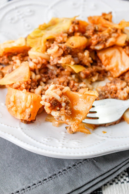 a fork scooping Cabbage Roll Casserole from a white plate.