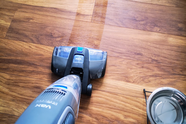 Image of the VAX ONEPWR Hard Floor Cleaner being used in wash mode on a dark oak laminate floor with a dog bowl just in shot.