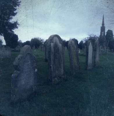 Grey filtered image of a row of headstones on a cemetery