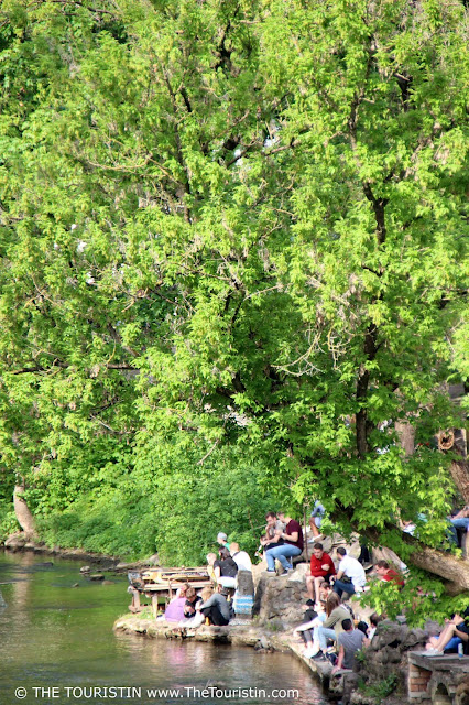 People sitting by the river on a warm summer day in Užupis in Lithuania