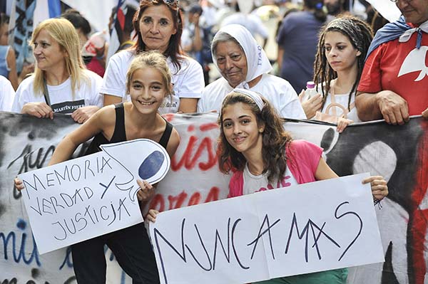 jóvenes y ancianos en una manifestacion con carteles de nunca mas y memoria verdad y justicia