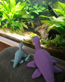 knitted nessie plesiosaurs in turquoise and purple by an aquarium