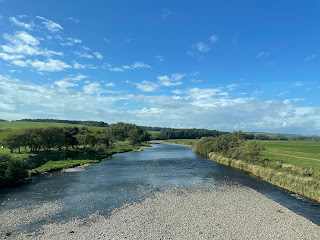 The River Lune on a sunny day, surrounded by grassy fields on either side.