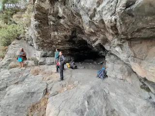 The cave up close, 3 people stand in the entrance looking out