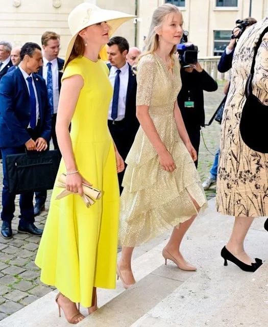Princess Eleonore wore a ruffled midi dress by Maje. Princess Elisabeth wore a yellow dress. Queen Mathilde wore a red dress