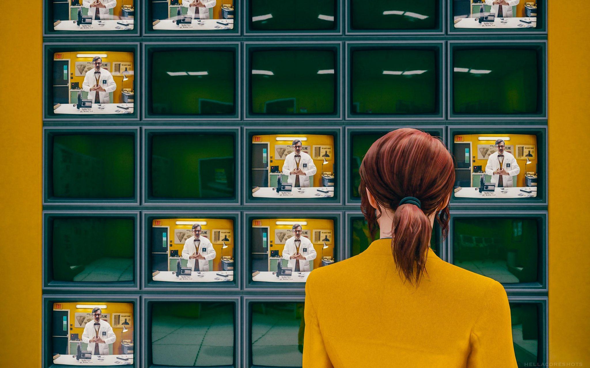 Jesse wearing her gold suit, stands in front of a series of screens showing a pre-recorded message from Casper Darling. [Image by hellacoreshots on Twitter.]