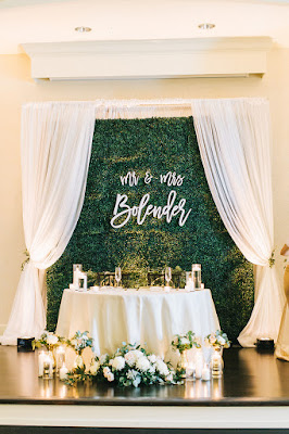 sweetheart table flowers and hedge wall with name