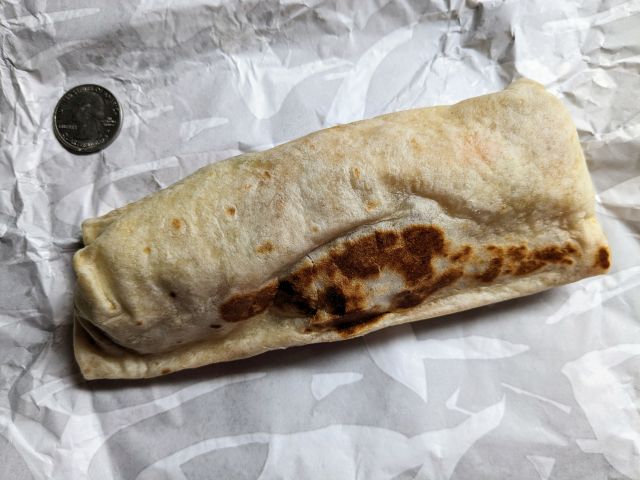 Taco Bell's Cantina Chicken Burrito next to a quarter.