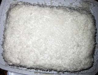White cake covered with coconut over the frosting