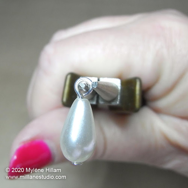 A pearl teardrop strung on a head pin with a simple loop on the jaws of round nose pliers.