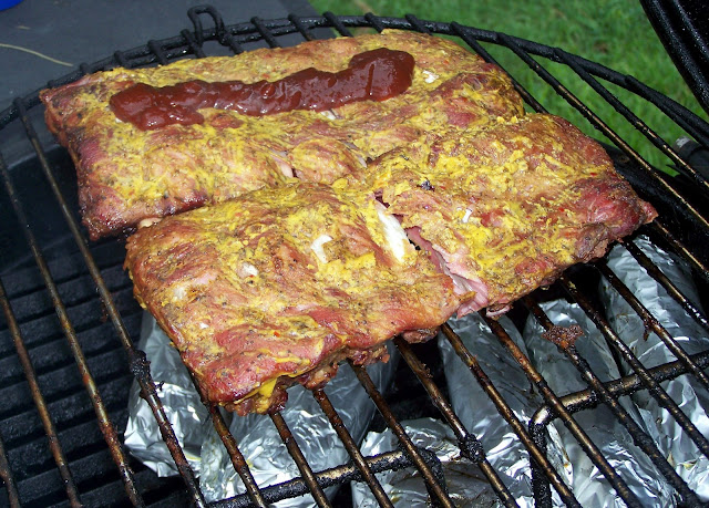 Two slabs of ribs being covered with bbq sauce