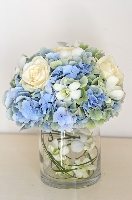 Low table centre of hydrangea, roses and orchids in pale blues,greens 