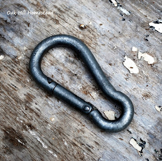 A snap clip (carabiner) on a wooden background.