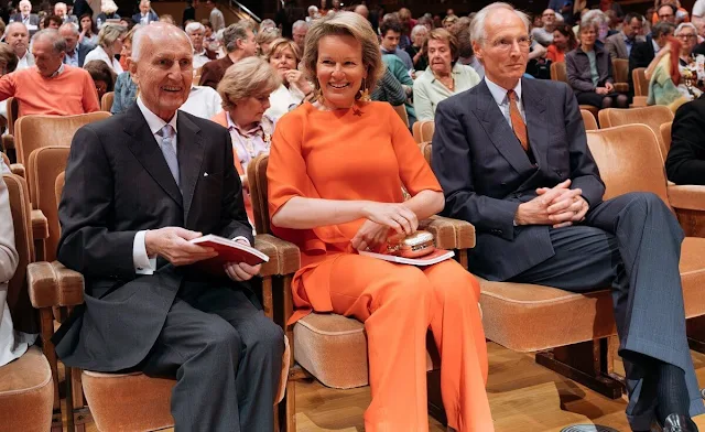 Queen Mathilde wore an Adria orange asymmetric jumper by Natan, and Natan Milan orange trousers. Gold flower earrings