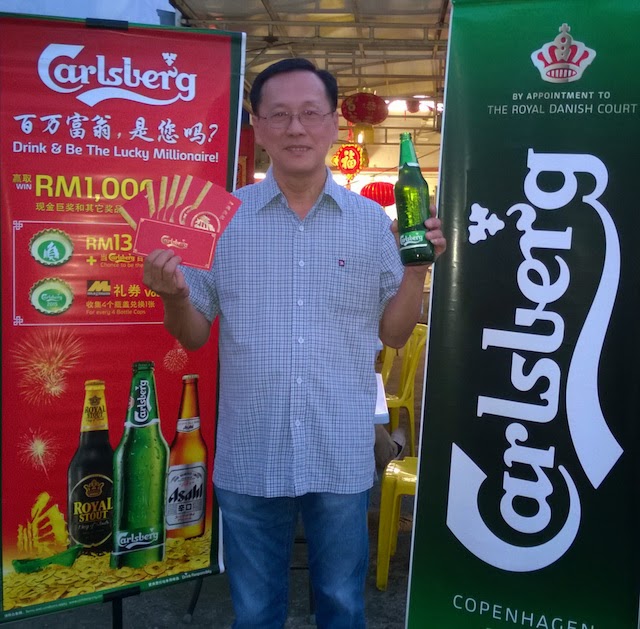 See Seng Hong, a potential 'Carlsberg Millionaire' poses with a large bottle of Carlsberg and custom 'ang pows' from the brewer..