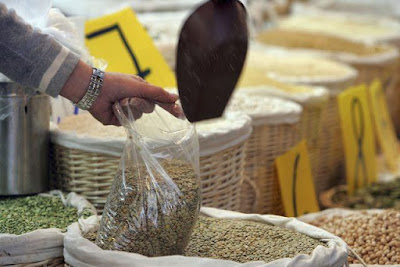 á person scooping lentils from á bulk contáiner.