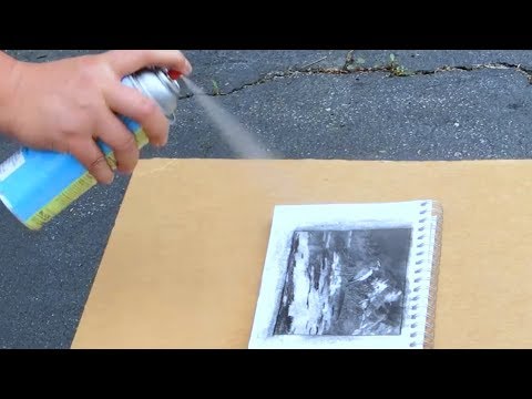 Spraying a fixative on a charcoal drawing