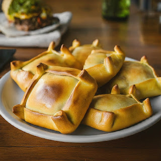 A detailed close-up of a plate of Chilean empanadas, highlighting their diverse fillings and perfectly golden-brown crusts