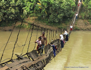 Students make their way across a damaged suspension bridge to go to their school on the other side of Ciberang river in Lebak,