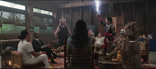 The supervillain support group plus Jen. Jen, Man-Bull, Blonsky, Dirk, Saracen, and Porcupine are seated, while El Aguila is standing, his sword drawn and electricity arcing from it.