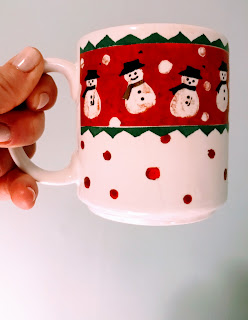 Holding a holiday mug with snowmen in scarves.