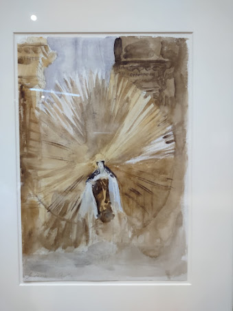 Photo of a watercolor in shades of gold, white, and beige, depicting a woman with a halo the size of her body.