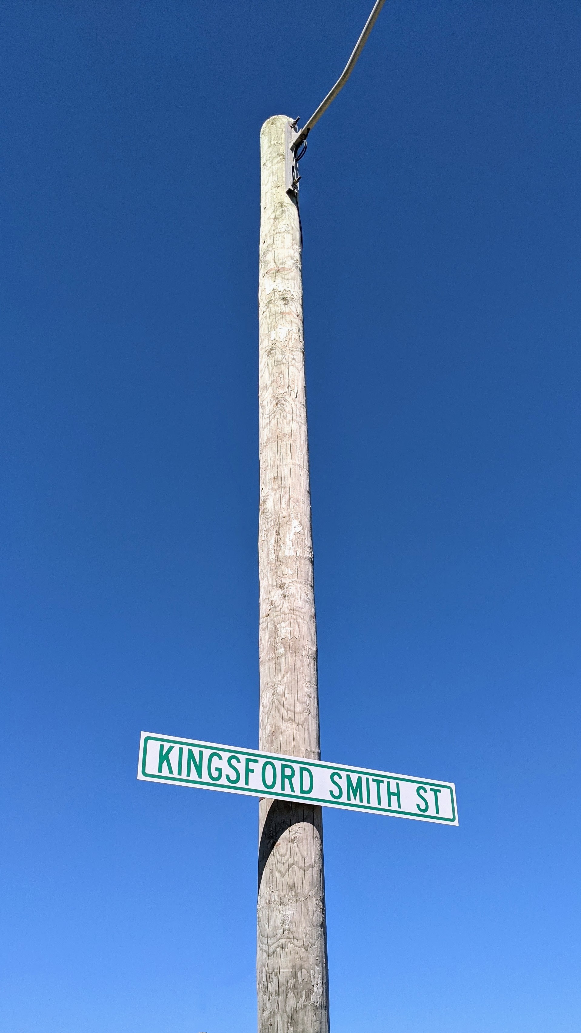 Kingsford Smith Street sign on a very tall post against a blue summer sky