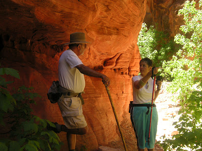 The reflected light in the slot canyon casts a red glow on Larry and Gwen as they examine the rock formations