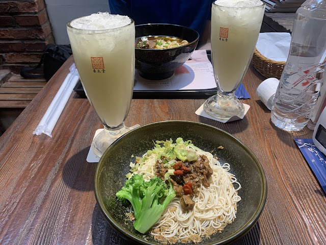 Two bowls of noodles and two iced drinks on a wooden table