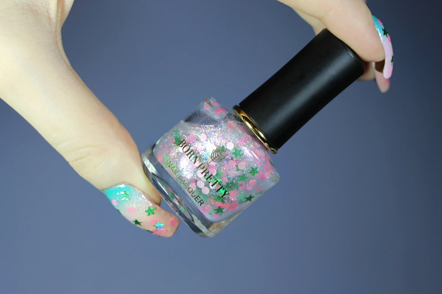 close-up of female hand with a glitter and sequin nail look in soft baby pink colors