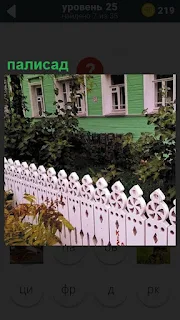 Около дома сделан палисад, розового цвета резной забор с узорами