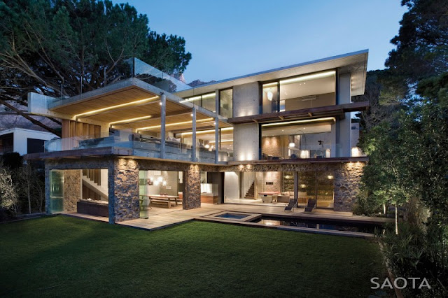 Photo of incredible modern home as seen at sunset from the lawn in the backyard