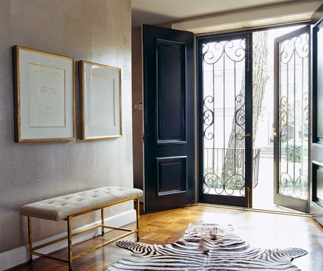 beautiful modern entry foyer with gold metal bench cowhide rug black door metallic wallpaper